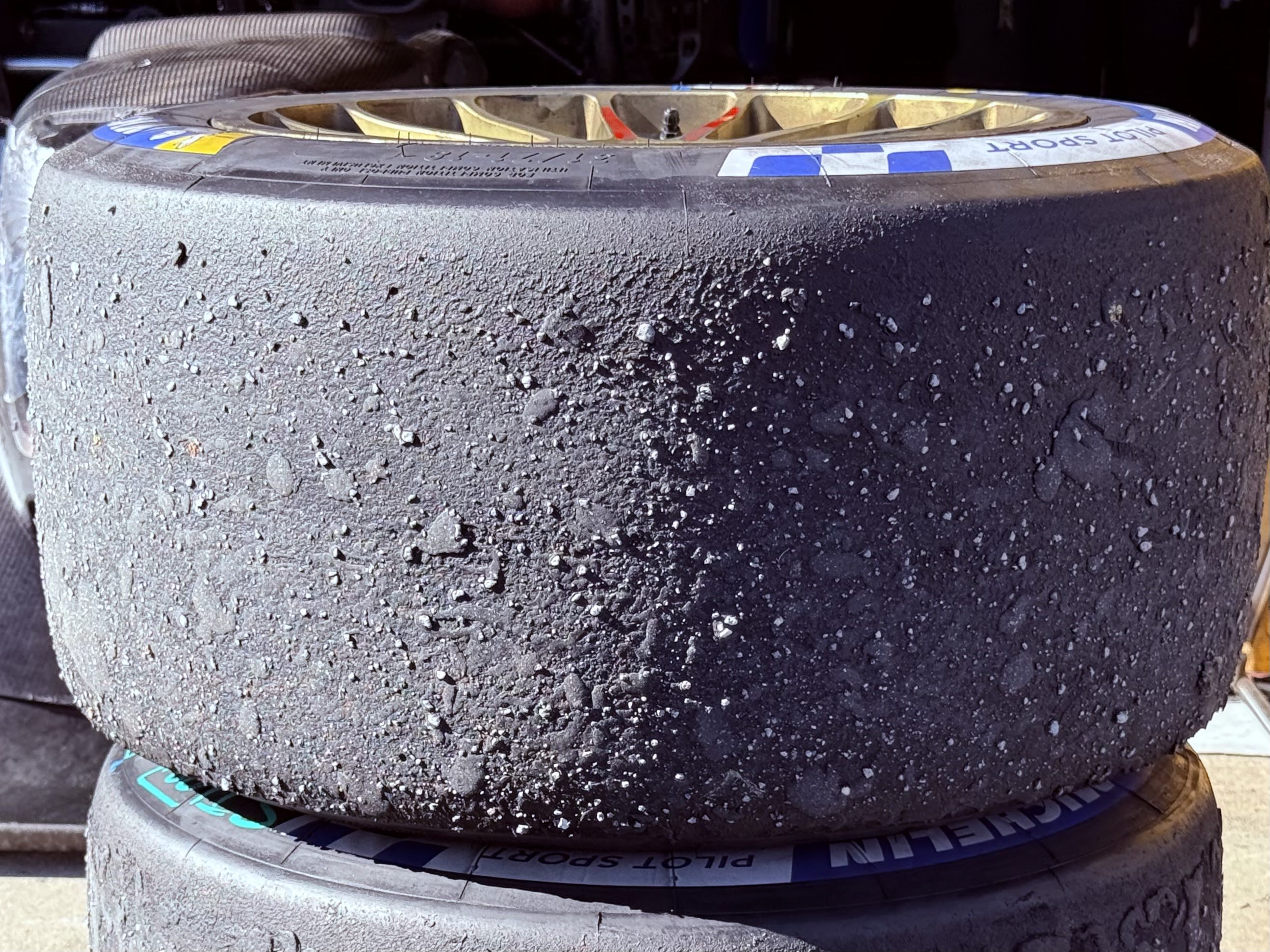 A close-up of the tread of a used slick Michelin race tire, which is very worn
